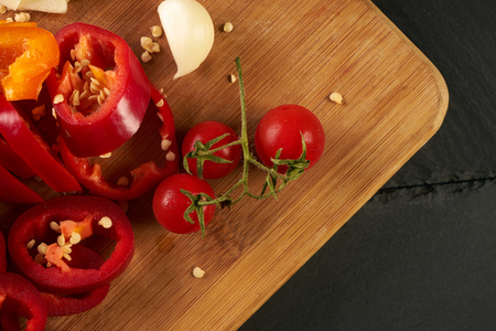 Fresh vegetables on cutting board, fresh juicy tomato, garlic, basil and bell pepper. Healthy Ingredients for vegetarian dish. Top view, closeupの写真素材