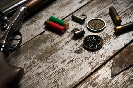 Hunting equipment. Shotgun shells hunting cartridges with gunpowder and many plumbeous fractions lead shot on wooden table background, close-upの写真素材