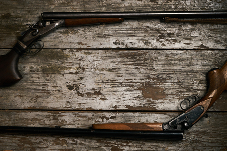 Double barrel hunting gun. Shotgun rifle on wooden table background with copy space for text, top view. Hunting equipment close-upの写真素材