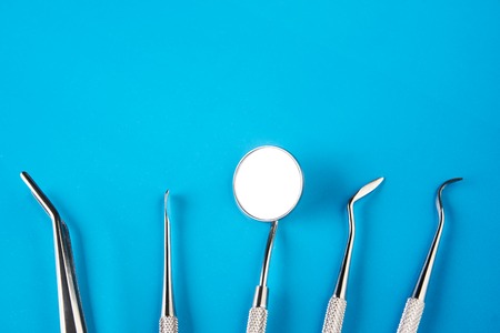 Set of Dentists medical equipment tools. Stainless steel dental equipment on blue background with copy space.の写真素材