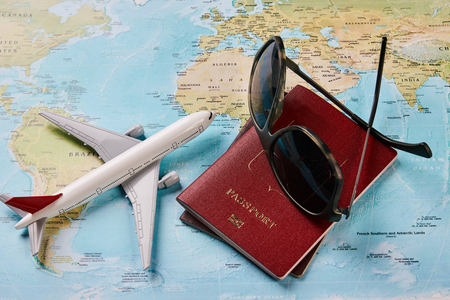 Airplane with two passports travel documents and sunglasses on the map of the world, holidays abroad. Plane worldwide travel planning concept. Traveling vacation concept, close-upの写真素材