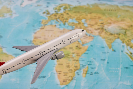 White toy plane on the world map background. Traveling, tourism, international flights with flying...