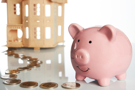 Pink piggy bank, coins trail and a house isolated on white background, Real estate or home savingsの写真素材