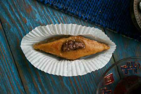 Pakhlava or baklava with nuts and honey. Novruz tray with Azerbaijan national pastry and drinking glass of black tea on blue rustic wooden table background, top view. Delicious dessert holiday foodの写真素材