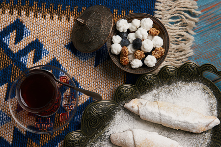 Homemade Mutaki roll cake with walnuts and sugar powder, oriental sweets mutaki pastry and traditional glass of black tea on rustic wooden blue table background, close-upの写真素材