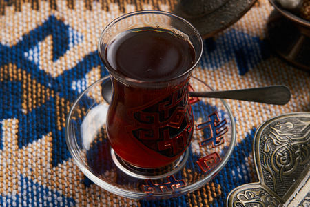 Homemade Mutaki roll cake with walnuts and sugar powder, oriental sweets mutaki pastry and traditional glass of black tea on rustic wooden blue table background, close-upの写真素材
