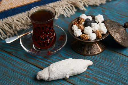 Biscuits with walnuts and powdered sugar, oriental sweets mutaki on rustic wooden table with traditional turkish tea and sweet snack in silver bowl, top viewの写真素材