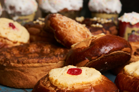 Homemade Russian Easter baked goods, kulichi, patties with cottage cheese, karavai and loaf cake with nuts on festive table backgroundの写真素材