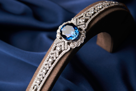 Beautiful platinum bracelet. Luxury women bracelet with diamonds and sapphire on blue silk background, close-upの写真素材