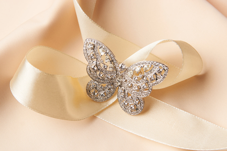 Brooch in shape of butterfly with diamonds on peach satin background. Luxury female jewelryの写真素材