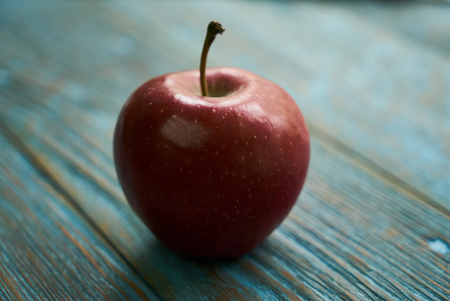 Fresh red apple on rustic wooden blue table background, close-up