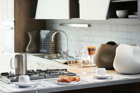 Delicious croissant and a two cup of coffee on a kitchen counter. Healthy breakfast with coffee in sunny morning for two person in modern kitchen interiorの写真素材