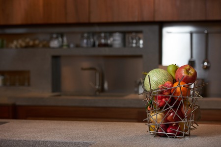 Fresh tropical fruits in abstract vase on kitchen counter table in luxury modern kitchen interior. Healthy vegetarian diet food and detox concept. Close-up, copy spaceの写真素材