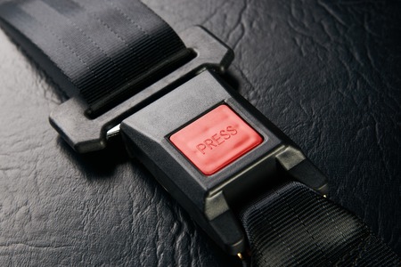 Fastened seat belt on black leather background, close-up. Safety concept