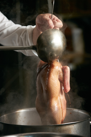 Chef is cooking beijing duck in the kitchen of restaurant. Peking Duck is a famous duck dish from Beijingの写真素材