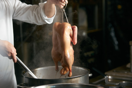 Chef is cooking beijing duck in the kitchen of restaurant. Peking Duck is a famous duck dish from Beijingの写真素材