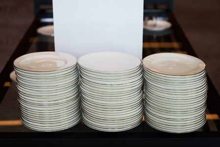 Stacked white ceramic plates for serving food on kitchen table of a restaurant. Copy spaceの写真素材
