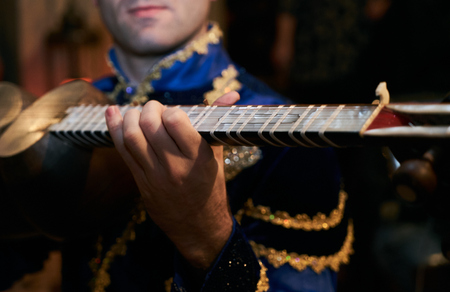 Man playing on a classical folk instrument tar of Azerbaijan.