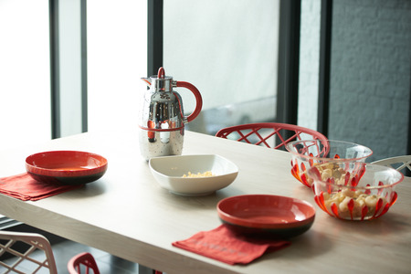 Breakfast with flakes and milk kettle on table in beautiful modern kitchen interior with large...