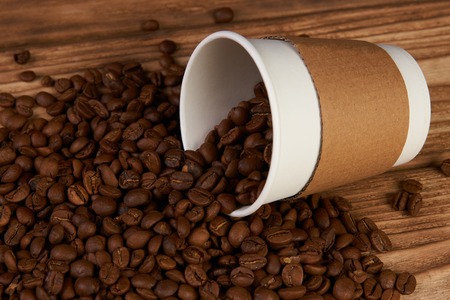 Take away coffee paper cups and roasted coffee beans on rustic wooden table background, close-up.の写真素材