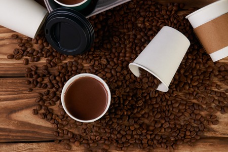 Composition with Takeaway coffee paper cups with hot chocolate drink and roasted coffee beans on...