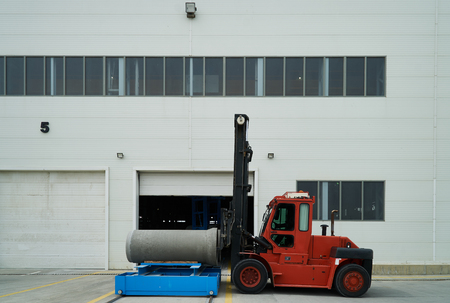 Heavy Forklift loader for warehouse works outdoors with concrete pipes. Industrial production of...