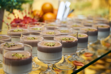 Dessert chocolate yogurt pudding in a glass on reception table in restaurant, close-up.