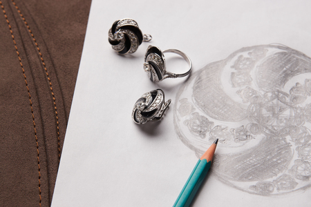 Beautiful diamond earrings and a ring with a picture on white paper. Luxury jewelry, close-up. Selective focusの写真素材