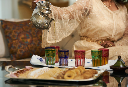 A woman Pours Moroccan Tea from Traditional moroccan Teapot into cups. の写真素材