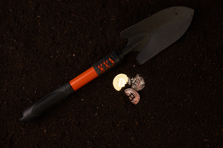 Bitcoin mining from the soil. Bitcoin gold coins, silver and bronze and shovel gardening tool. Virtual cryptocurrency mining concept.の写真素材