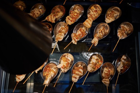 Chicken Shish kebab on wooden skewers in silver bowls on a banquet buffet table, top viewの写真素材