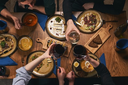 Table with food top view. People eat healthy meals at festive table served for party. Friends celebrate with organic food on wooden table view from above. Happy company having lunch, taking salad dishの写真素材
