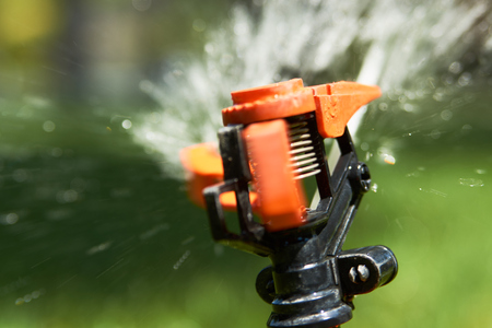 Close up sprinklers spraying water on grass lawn irrigation at early morning. Smart garden activated with full automatic watering. Eco irrigation systemの写真素材