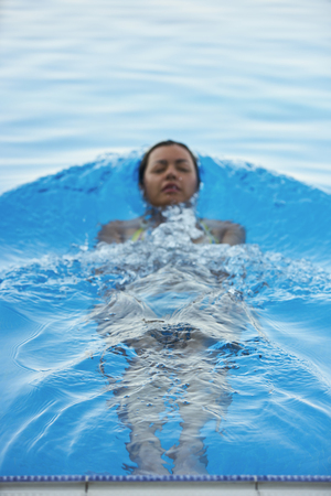 Woman tourist swimming in infinity pool of hotel resortの写真素材