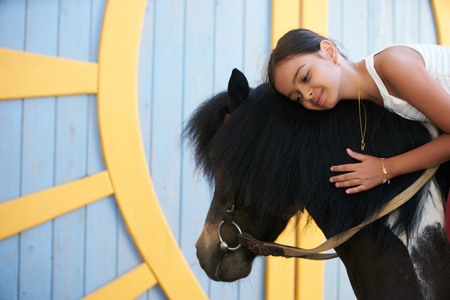 Portrait of young girl with horse. Young cute girl having fun with horseの写真素材