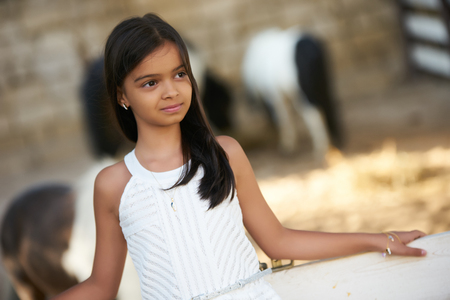Beautiful young girl and horses. Cute smiling girl with long dark hearの写真素材