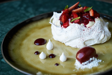 Summer fruit cake dessert Paclova. Served meringues pavlova cake with fresh berries and custard cream, close-upの写真素材