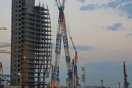Industrial Construction cranes and buildings against the evening sky. Building tower crane and unfinished building under constructionの写真素材