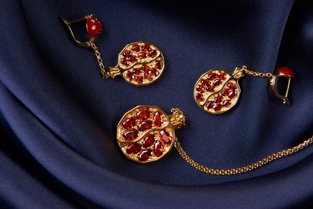 Ruby necklace and earrings on blue silk background with copy space. Beautiful precious womens gold jewelry, close-up.の写真素材