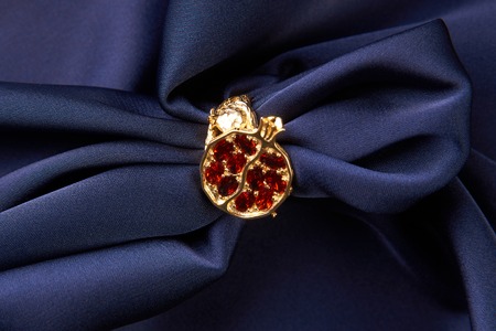 Wedding jewelry, golden ring with red rubies, gemstone engagement. Beautiful precious womens jewelry ring on blue silk background with copy space.の写真素材