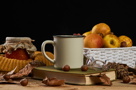 Autumn leaves, cup of coffee, warm scarf, fruits basket , jam jar, book with glasses on the table on black background, close-up. Morning breakfast seasonal book reading, Sunday relaxing conceptの写真素材