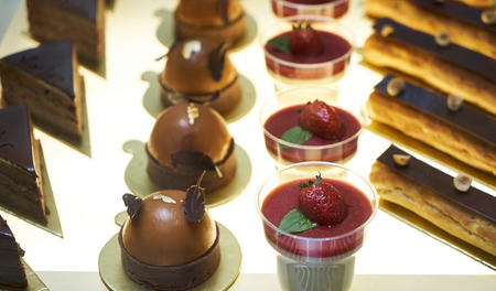 Cake shop with sweets on showcase table, close-up. Different types of cakes pieces in pastry shop...