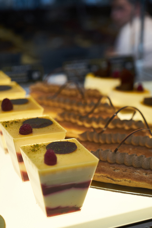 Cake shop with sweets on showcase table, close-up. Different types of cakes pieces in pastry shop...