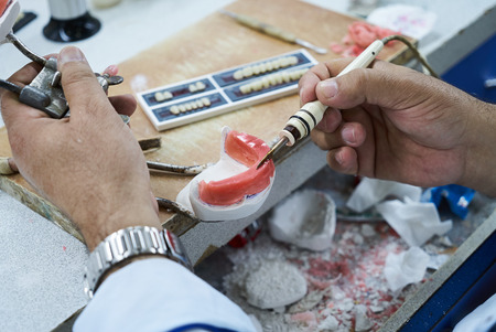 Dental technician or dentist working with tooth dentures in his laboratory, close-up