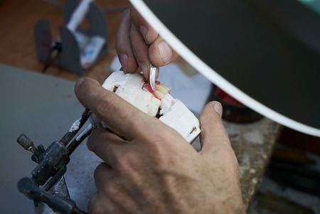 Dental technician working with articulator in dental laboratory, close-up. Dentist hands holds prosthesis on a plaster jaw his labの写真素材