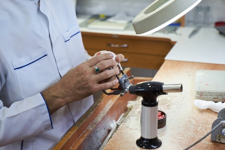 Dental technician working with articulator in dental laboratory, close-up. Dentist hands holds prosthesis on a plaster jaw his labの写真素材