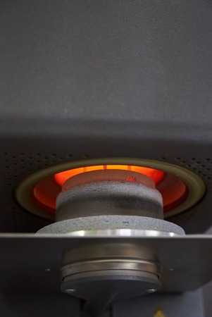 Oven and press for ceramic dental prostheses, in action, close-up. Ceramic teeth ready for baking in...
