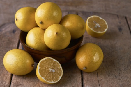 Fresh Juicy Lemon cut on wooden table, close-up.  Yellow lemons in a wooden bowl on wood background with copy spaceの写真素材