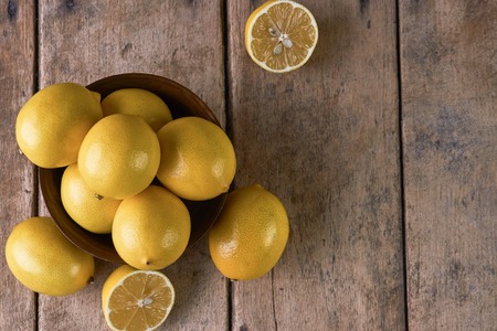 Fresh Juicy Lemon cut on wooden table, close-up, top view. Yellow lemons in a wooden bowl on wood background with copy spaceの写真素材