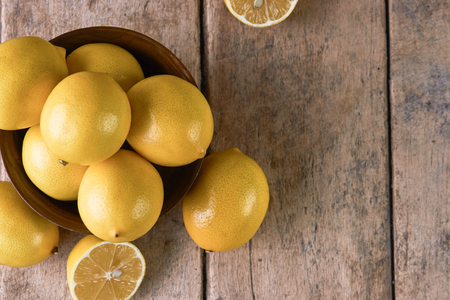 Fresh Juicy Lemon cut on wooden table, close-up, top view. Yellow lemons in a wooden bowl on wood background with copy spaceの写真素材